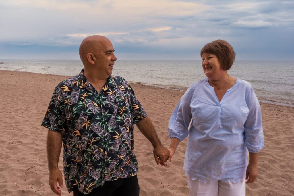 Man and woman walk hand-in-hand down the beach
