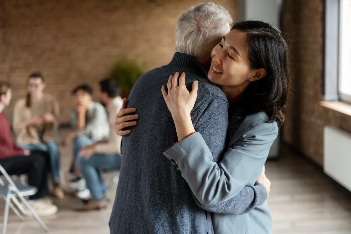 Elderly man hugging his caretaker