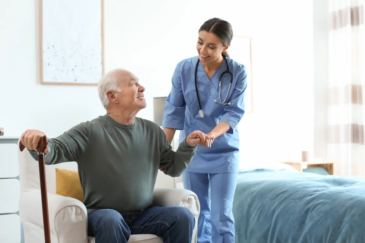 Caretaker helps elderly man stand up