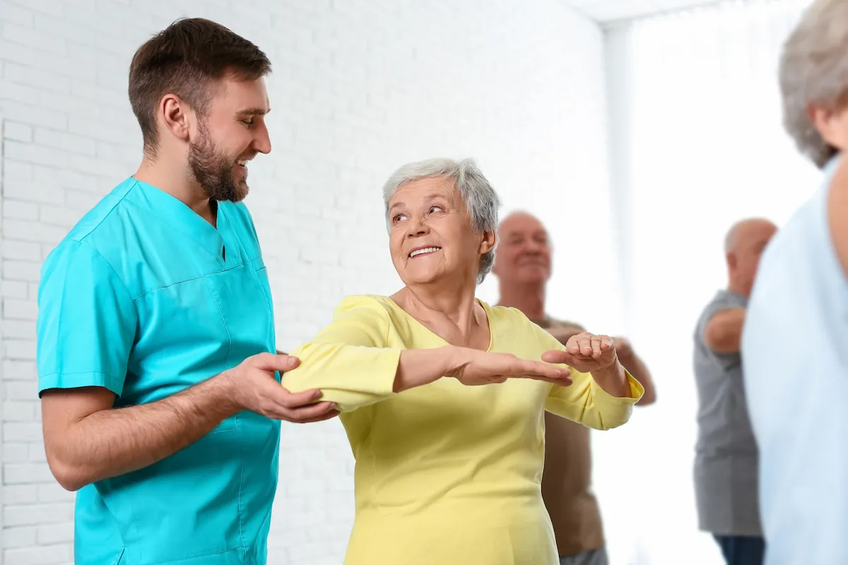 Health professional helping an elderly woman exercise
