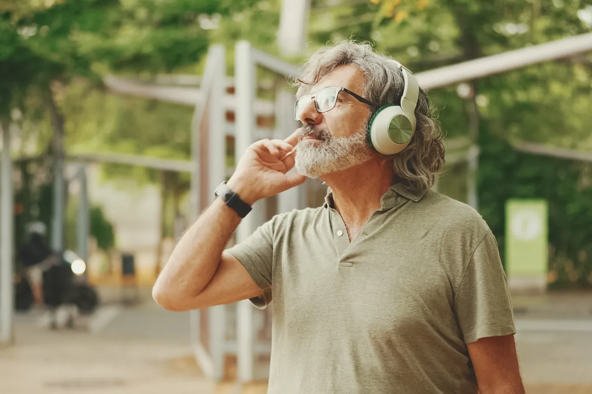Older man listening to headphones in the park
